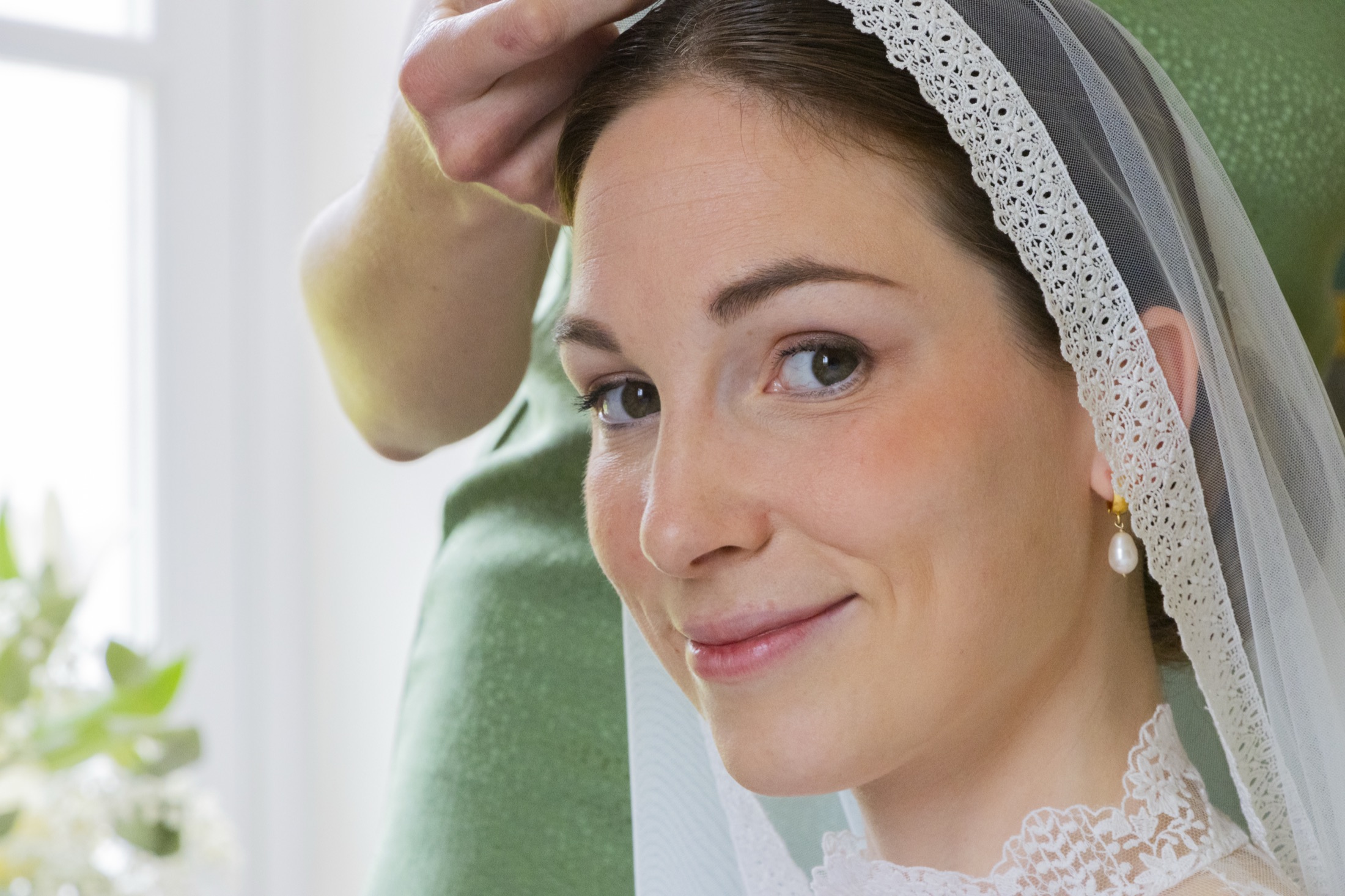 Portrait de la mariée pendant la pose du voile