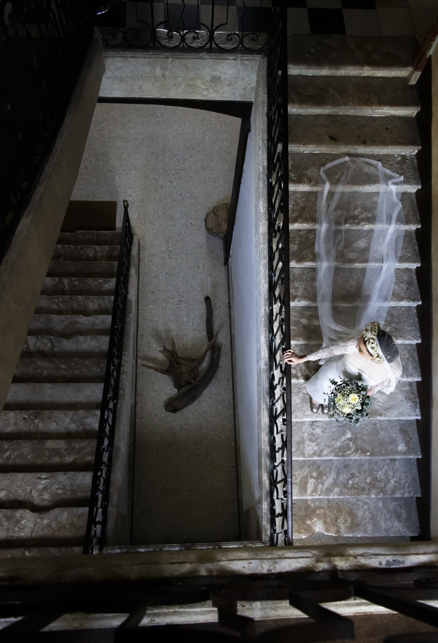La mariée vue d'en haut dans un escalier de pierre, le voile déployé